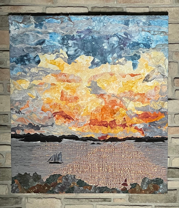 A colorful mosaic depicts a dramatic sunset over water with a sailboat in the distance. The sky transitions from deep blue to orange and yellow, blending with textured stone pieces, creating a vivid landscape.