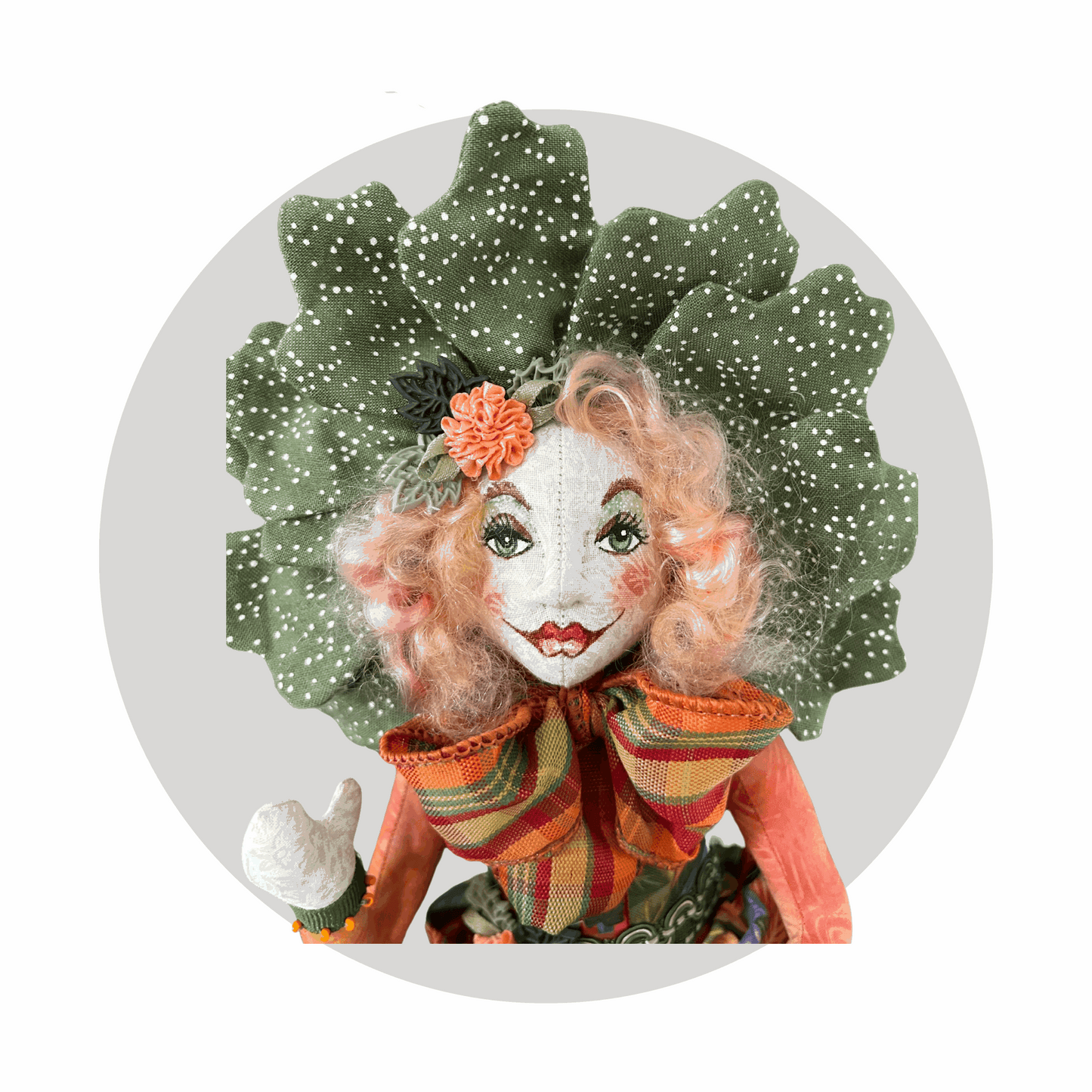 Fernadilly by Mary Cantore is a unique art doll with a hand-painted face—red lips, green eyes, curly pink hair, a leafy white-dotted headpiece, and big striped bowtie—set against a light grey circular background.