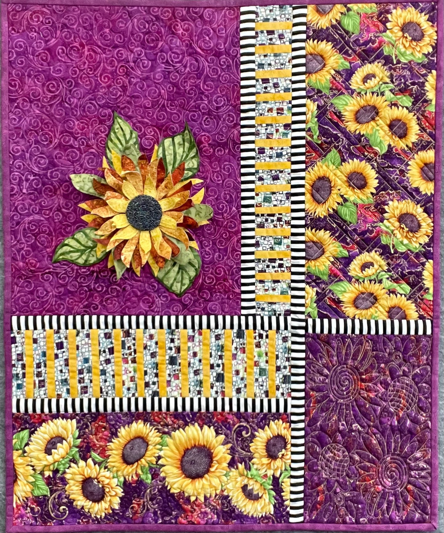Following the Sun: Quilted Wall Art by Mary Cantore showcases vibrant sunflowers, purple swirls, black-and-white stripes, and a 3D sunflower appliqué—ideal as a bold, textured wall hanging.