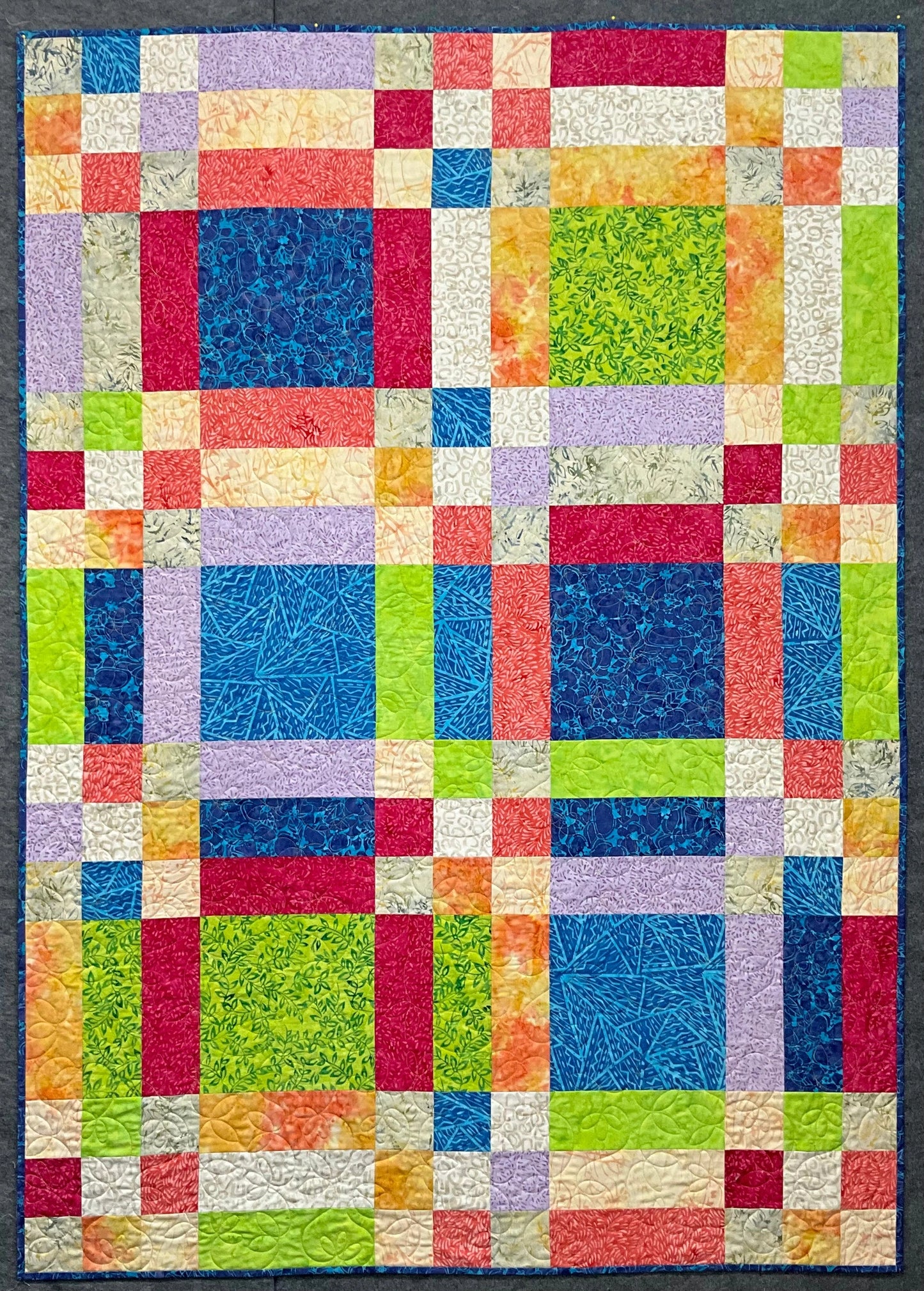 The Popsicle by Mary Cantore is a vibrant lap quilt with a geometric design, featuring a patchwork of green, blue, red, yellow, purple, and orange squares that bring Fat Quarter Quilting Fun to life.