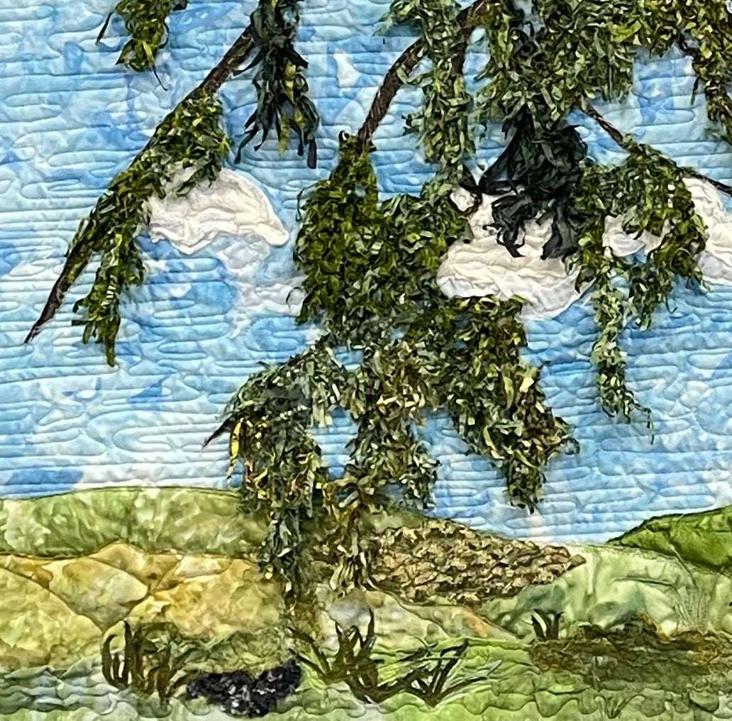 The Looking Up: Landscape Textile Art Wall Hanging by Miki Howell is a handcrafted quilt featuring a green tree branch with leaves against a blue sky and clouds, overlooking rolling green hills and grassy fields.