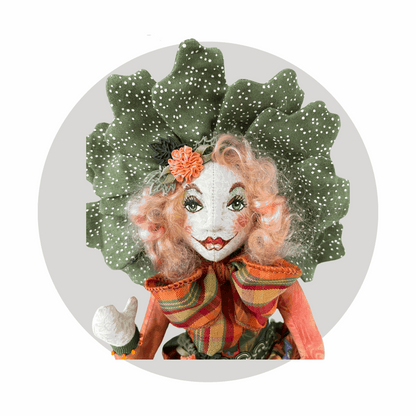 Fernadilly by Mary Cantore is a unique art doll with a hand-painted face—red lips, green eyes, curly pink hair, a leafy white-dotted headpiece, and big striped bowtie—set against a light grey circular background.