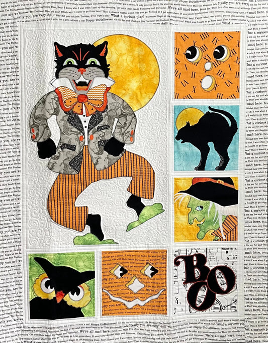 The Boo: Quilted Wall Art by Mary Cantore features machine quilting and raw edge applique, depicting a black cat in a suit, full moon, owl, BOO text, green witch, bats, jack-o’-lanterns, and more on newspaper print.