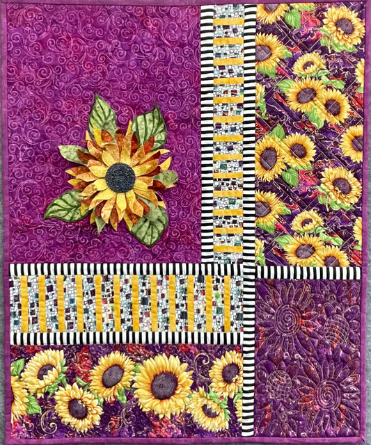 Following the Sun: Quilted Wall Art by Mary Cantore showcases vibrant sunflowers, purple swirls, black-and-white stripes, and a 3D sunflower appliqué—ideal as a bold, textured wall hanging.