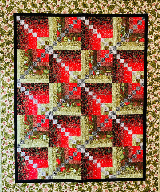 Holiday Spice: Quilted Wall Art by Mary Cantore features a log cabin patchwork in festive colors, bordered with floral fabric and a black frame—perfect as cozy holiday decor or to add seasonal charm to any room.