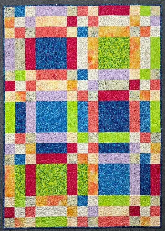 The Popsicle by Mary Cantore is a vibrant lap quilt with a geometric design, featuring a patchwork of green, blue, red, yellow, purple, and orange squares that bring Fat Quarter Quilting Fun to life.