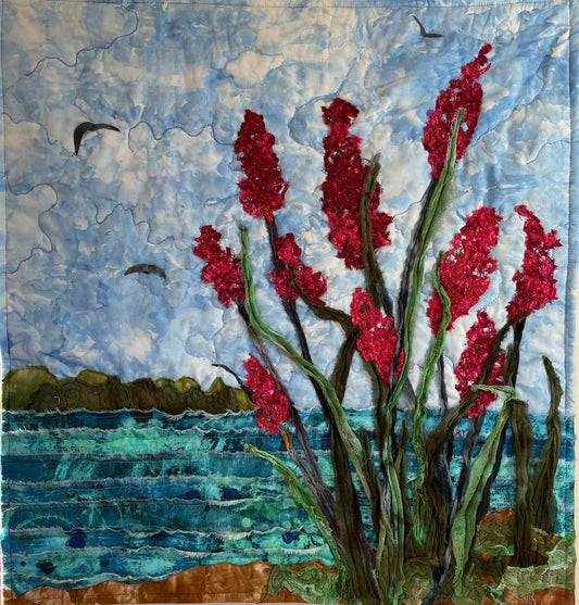 Sweet Calm: Seascape Art Quilt by Miki Howell features tall red flowers with green stems near a blue body of water, distant land, birds in flight, and a textured layered design for unique textile wall art.