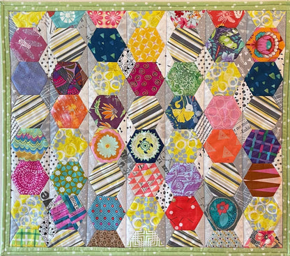 Hexi Fun: Art Quilt by Miki Howell is a colorful wallhanging with octagons, diamonds, and Hexi Fun patterns in vibrant yellow, pink, blue, green, and orange shades, bordered by light green fabric using English paper piecing.
