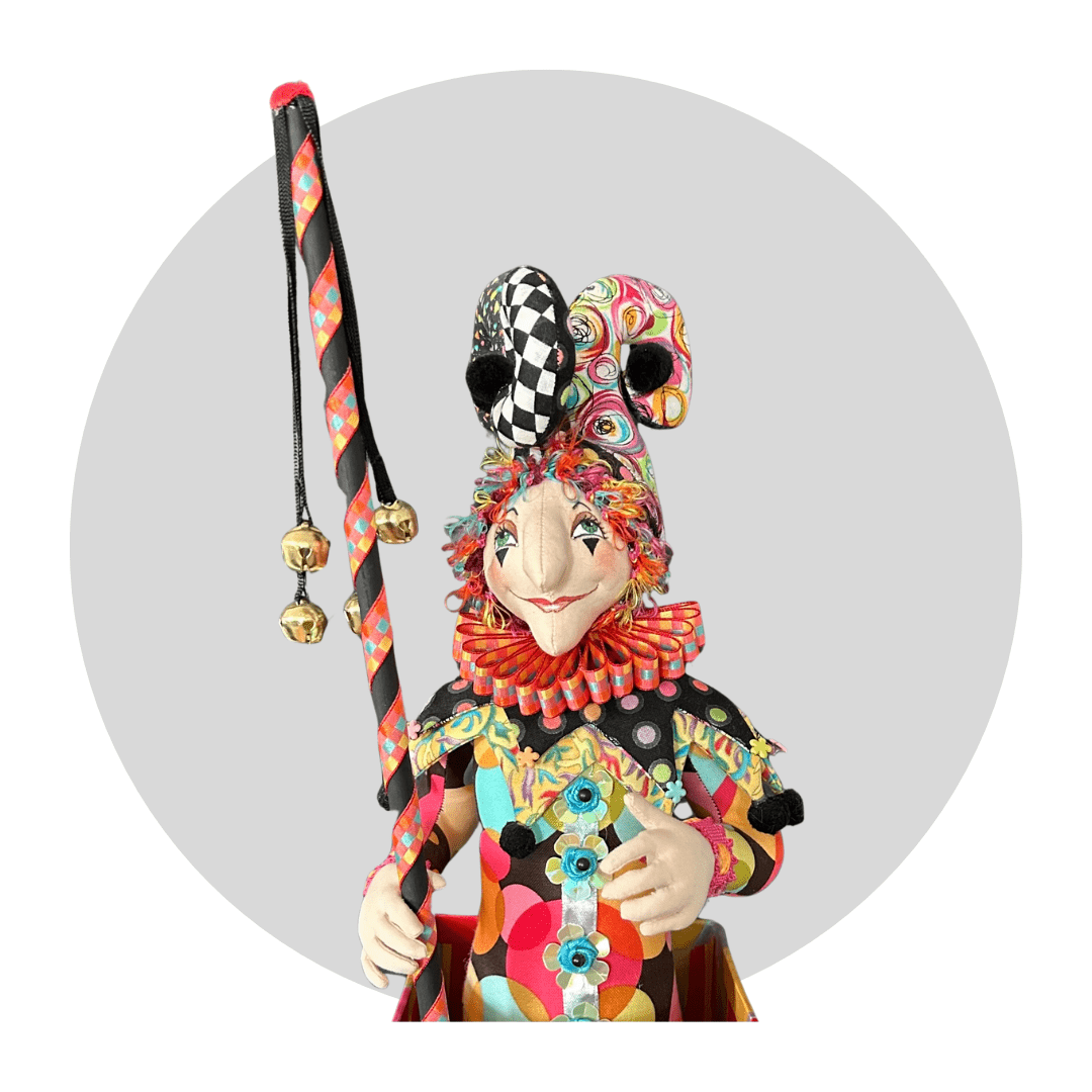Jack Jack itb: An Art Doll by Mary Cantore is a whimsical jester with a patterned suit, ruffled collar, playful hat, and ribbon-adorned staff, shown against a plain gray circular background.